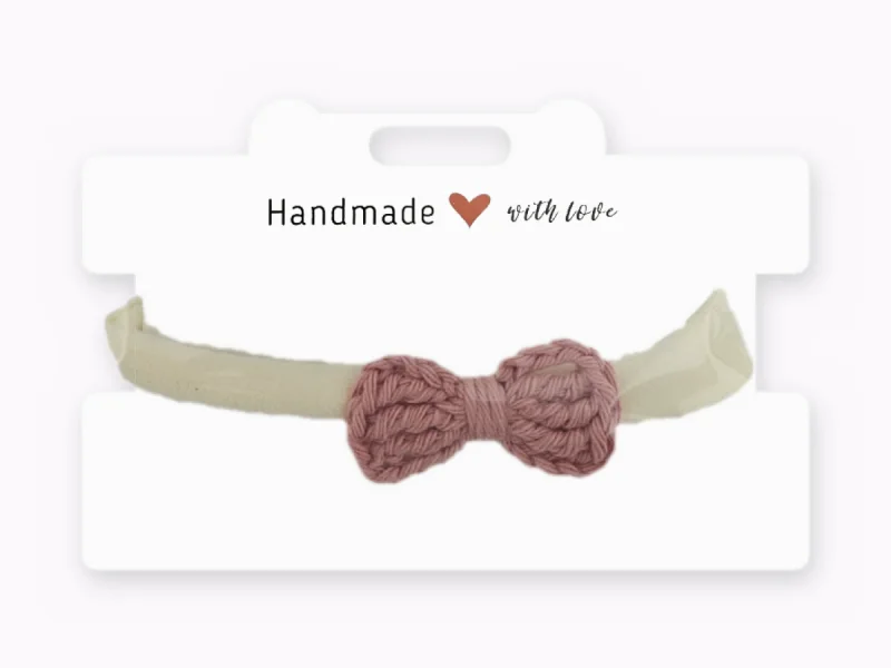 Cream baby headband with a small dusty pink crocheted bow, on a Handmade with love card